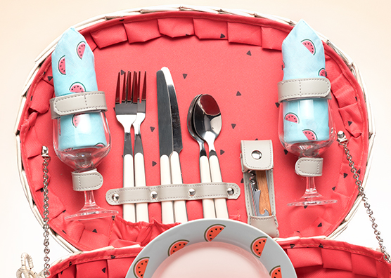 An open picnic basket with cutlery and glasses with a watermelon print