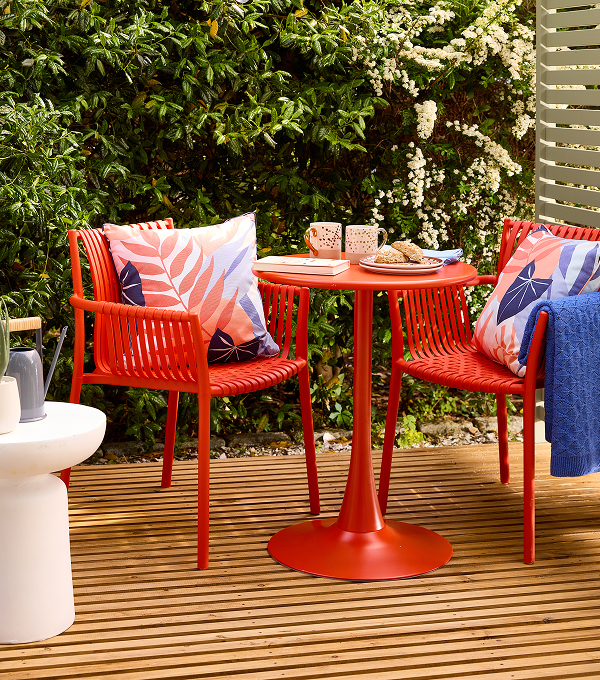 A garden with bold tableware, printed cushions and a bright blue throw..