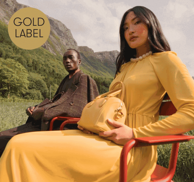 A female model wearing head-to-toe butter yellow outfit, with a male model wearing a smart brown suit.