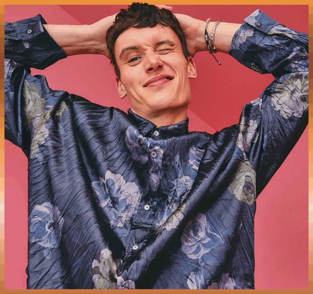 A smiling woman wearing a sparkling sequinned dress and chunky cocktail rings