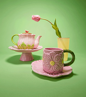 A floral embellished tea set, including a teapot, cake stand, mug and plate.