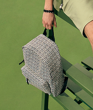 A closeup of a man holding a patterned backpack.