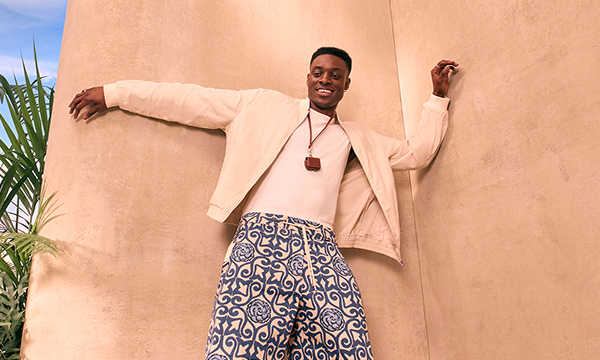A model wears a linen jacket and crisp white tee with printed long shorts.