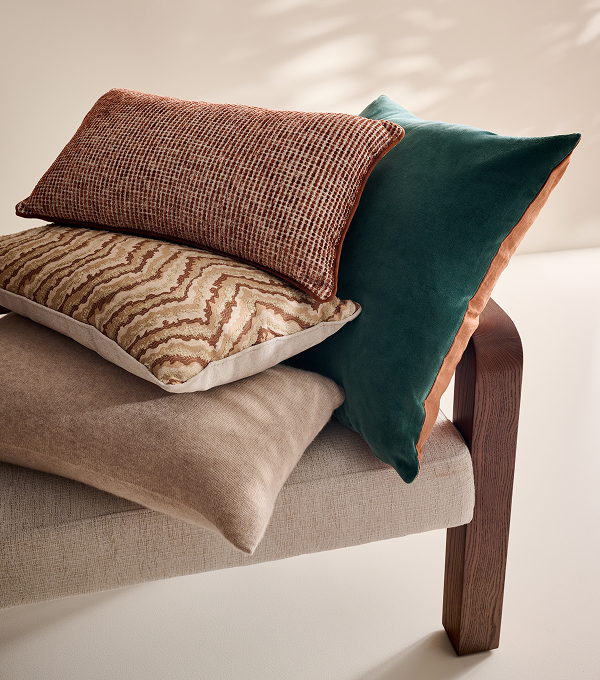 A selection of plush cushions on a beige stool.
