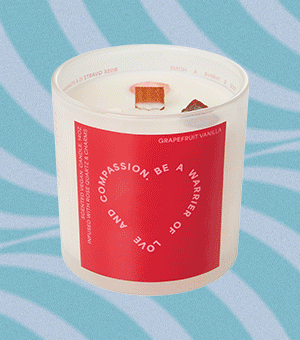 A scented candle in a glass jar with a bright red label.