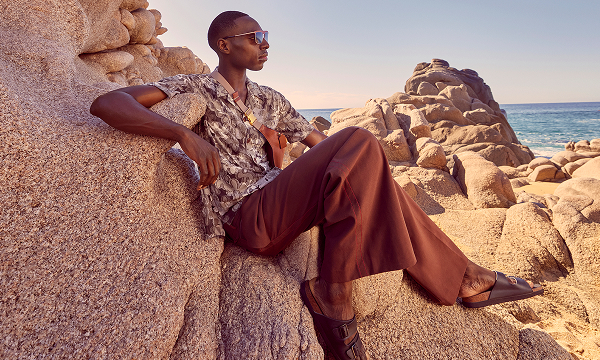 A male model wearing a short-sleeve shirt and burnt orange trousers. 