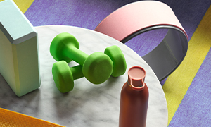 A mint green yoga block, green dumbbells and a burgundy water bottle.