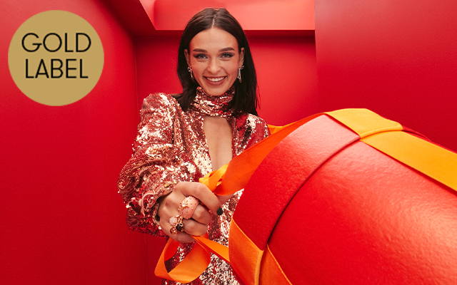 A female model wearing a sequin party dress and holding a gift box.
