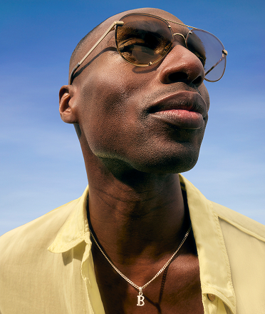 A male model wearing a butter yellow shirt and bold sunnies. 