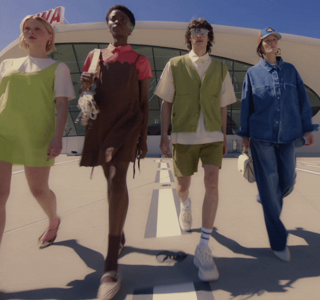 GIF of four models walking outdoors, dressed in bright, modern layered outfits.