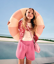 A child wearing a co-ord, holding a rubber ring.
