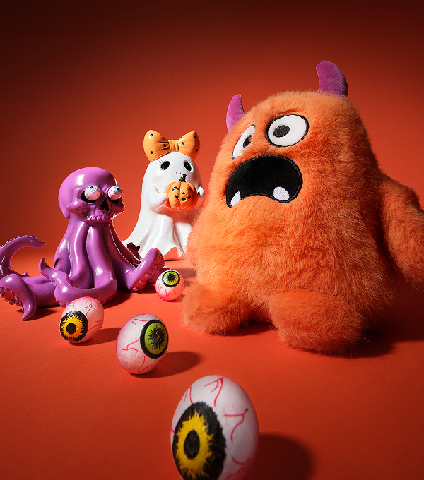 Halloween accessories and a plush monster against an orange background.