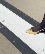 Cream pointed slingback shoe stepping across white road markings.