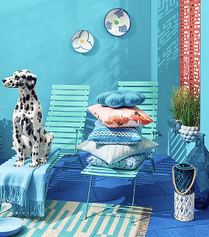 Blue lounge chairs and printed cushions placed on a printed outdoor rug.