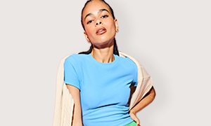 A male model wearing a striped tee, bright green jacket and waterproof hat. 