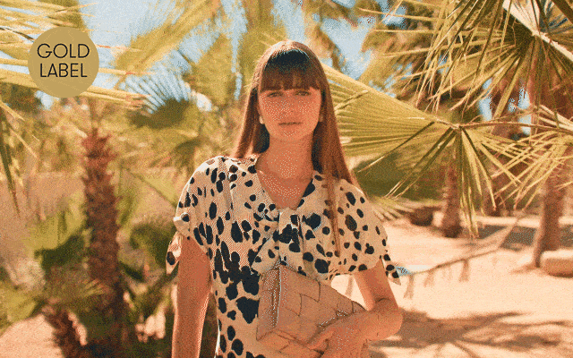 A GIF of a female model in the sun wearing a bold printed midi and open-toe heels. 