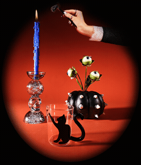 A glass candleholder with bright blue candle, black studded pumpkin and black cat glass.