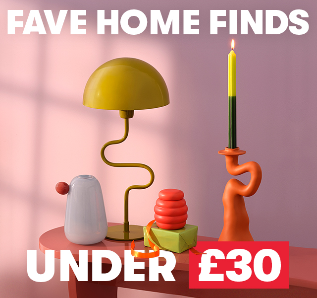 A selection of homewares including a bright orange abstract candlestic and a mustard yellow lamp.