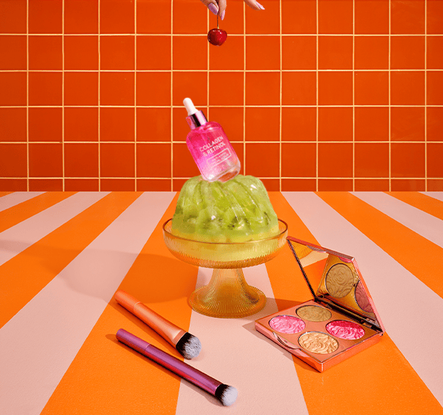 A green jelly on a pink and orange background, surrounded by branded beauty products.