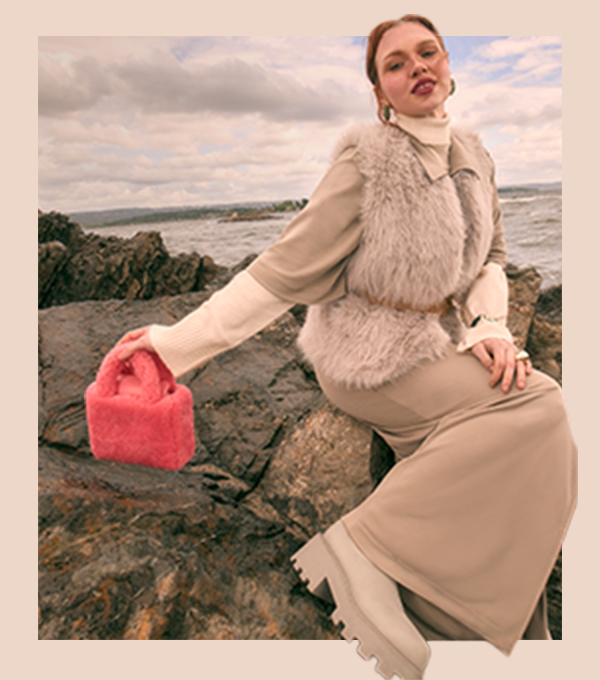 A model wearing a long dress and faux fur gilet