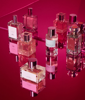 Five fragrances set on a mirrored surface.