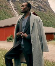 A man in sharp tailoring with a light grey woollen overcoat 