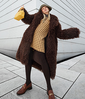 A model wearing a fluffy brown coat, yellow dress and matching bag 