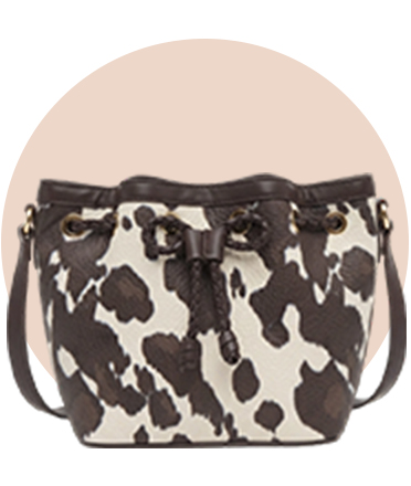 A cow-print bag against a beige circular background.