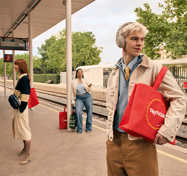 GIF showing three people stood at a train platform, all carrying a TK Maxx tote bag.