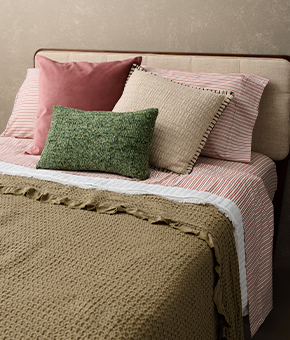 A perfectly made bed, decked out in neutral sheets, throws and pillows.