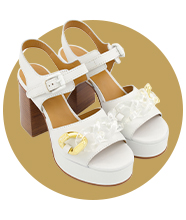 A pair of white platform heels with clear and gold acetate buckle details.