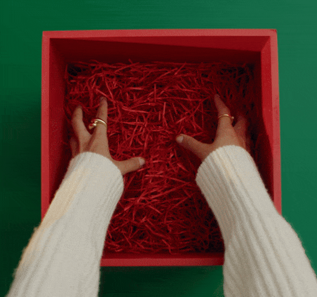 An overhead shot of a gift box being filled with festive goodies.
