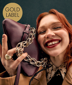 A smiling model carrying a burgundy leather handbag.