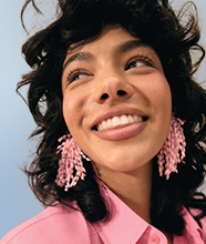  A model with dark hair wearing pink earrings