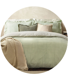 A bed with green striped bedding and pillows. 